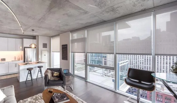 Estores enrollables en la cristalera de un loft con vista a la ciudad